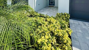 A modern two-story house with a garage, a covered entryway, and a well-maintained front yard with palm and shrubbery. - Beautiful Condo at Reunion (Kissimmee)