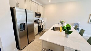 A modern kitchen with stainless steel appliances, a central island, and a sink. - Beautiful Condo at Reunion (Kissimmee)