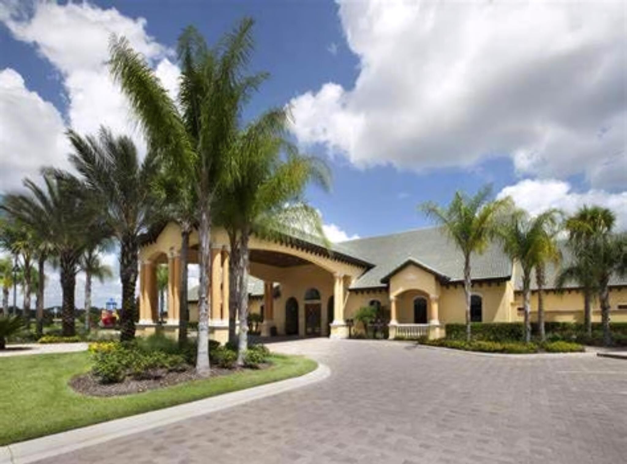 A hotel with a central courtyard, palm trees, and a clear sky.