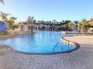 A swimming pool with a stone border, palm trees, and a clear sky. - Paradise Palms Resort, Just Minutes From Disney!!!! (Kissimmee)