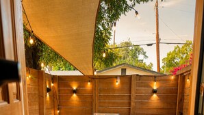 Une terrasse avec un barbecue, une chaise, une petite table et une plante en pot.