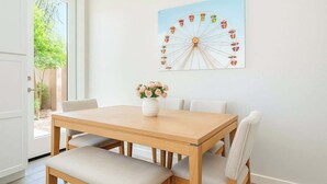 Ein Essbereich mit einem Holztisch und Stühlen, einer Vase mit Blumen und einem Wandbild einer Achterbahn.