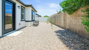 Ein modernes Gebäude mit einer gepflegten Schotterterrasse, einer Bank und einer Ziegelwand mit Bepflanzung.