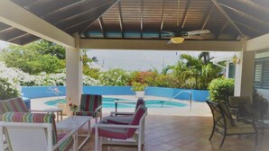 Un espace extérieur abrité comprenant une piscine, des chaises longues et une vue sur la végétation environnante.