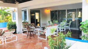 Un espace extérieur aménagé en terrasse, avec des meubles blancs, notamment des chaises et des tables, entouré de plantes en pot.