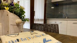A kitchen with a marble backsplash, a wooden table with a towel, and a wicker chair. - Holiday apartment with air conditioning and washing machine (Rosolina Mare)