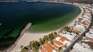 Ett flygbildsbild av en kuststad med en strand, klart vatten och berg i bakgrunden.