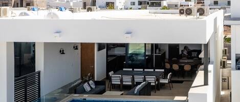 A modern building with a rooftop pool, a dining area, and a view of a mountain.