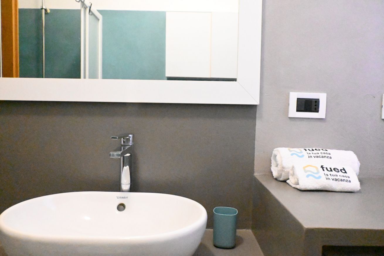 A bathroom with a white sink, a mirror, a towel, and a cup.