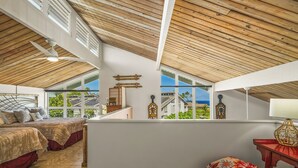 A bedroom with two beds, a ceiling fan, and a view of the outside.