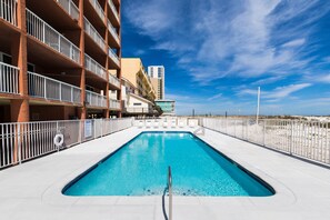 A rectangular swimming pool with a metal handrail, surrounded by a white fence and a white balcony railing. - Buena Vista 305 | Beachfront | Beach Side Pool in Gulf Shores | My Beach Getaways (Gulf Shores)