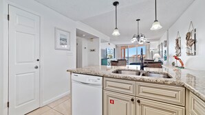 A kitchen with a dishwasher, granite countertop, and pendant lights. - Buena Vista 305 | Beachfront | Beach Side Pool in Gulf Shores | My Beach Getaways (Gulf Shores)