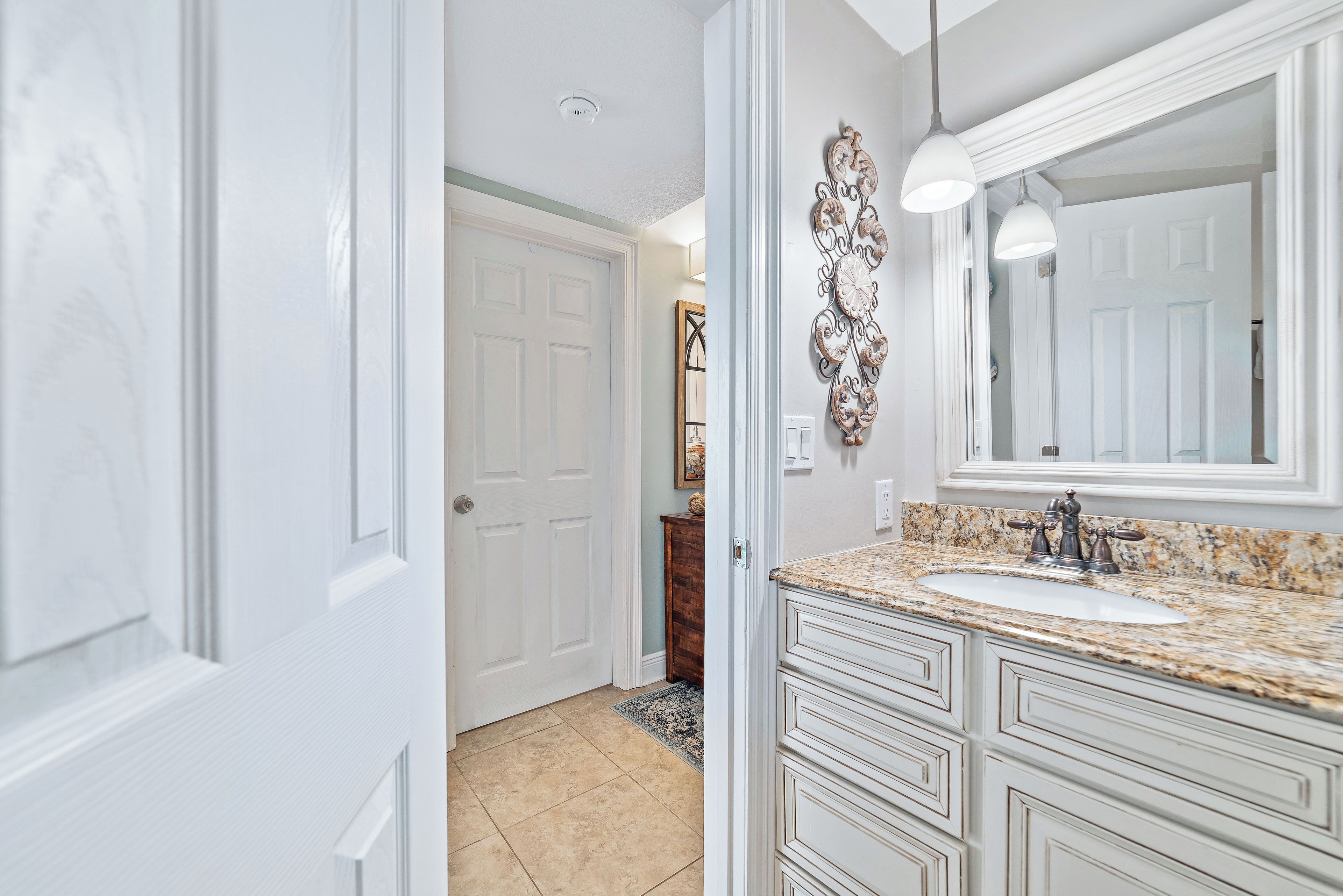A bathroom with a white vanity, a sink, and a mirror.