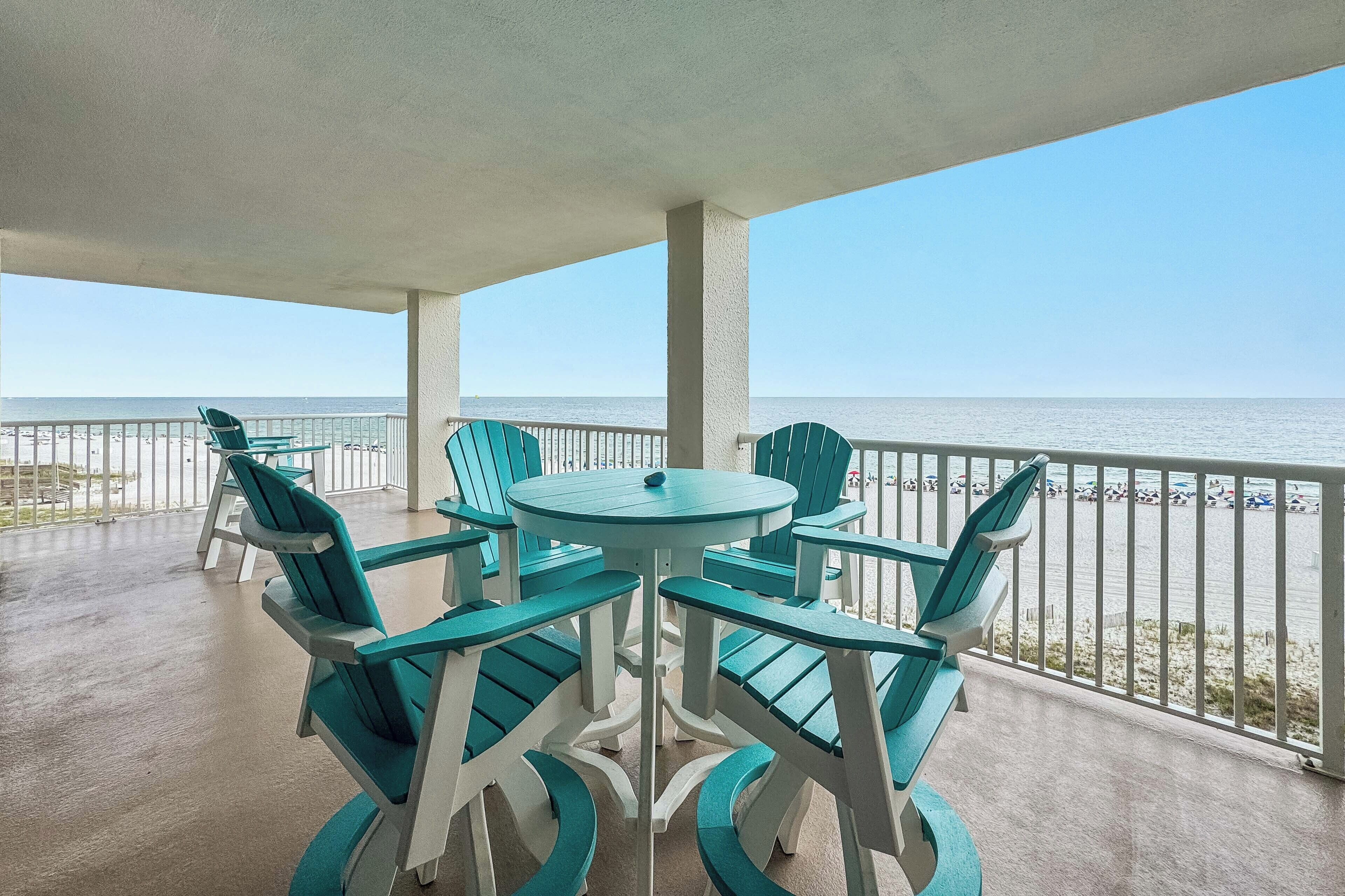 A covered outdoor seating area with a view of the beach and ocean.