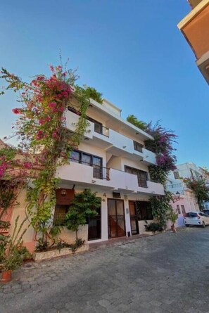 A multi-story residential building with balconies, a paved driveway, and potted plants. - Casa La Maria Colonial Zone TwoBedRoom (Santo Domingo)
