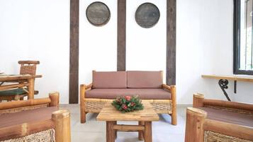 Une pièce chaleureuse avec un canapé en bois, deux décorations murales rondes et une petite table agrémentée d’un arrangement floral.