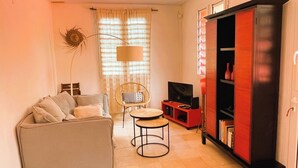Un salon avec un canapé, une petite table ronde, un meuble pour la télévision et une bibliothèque.