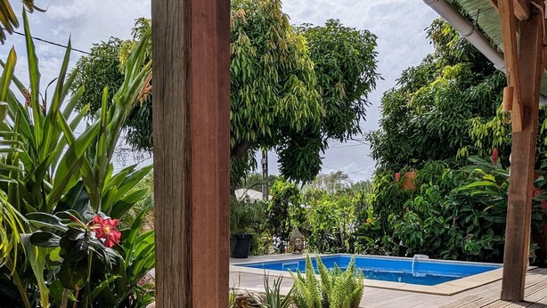 A wooden deck with a pool, surrounded by lush greenery and potted plants. - Villa Lazy Coco, a 3-minute walk from the sea (Sainte-Luce)