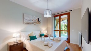 Een slaapkamer met een bed, nachtkastjes, een schilderij en uitzicht door een glazen deur.