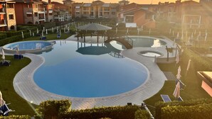 Een resort met een groot centraal zwembad, omringd door kleinere zwembaden, en een prieel.