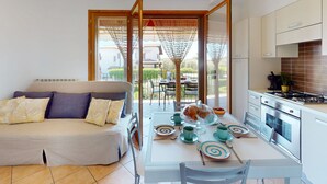 Una cocina moderna con armarios blancos, una estufa a gas y un comedor con mesa para dos.