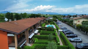 Un hotel con piscina, varios balcones y vistas a las montañas.