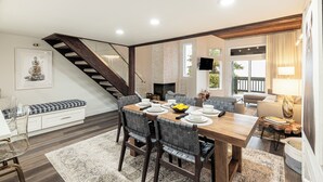 A modern dining area with a wooden table, chairs, and a staircase.