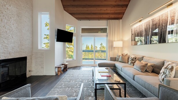 A modern living room with a fireplace, a sofa set, a coffee table, and a TV mounted on the wall.