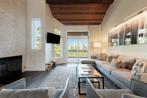 A modern living room with a fireplace, a sofa set, a coffee table, and a television mounted on the wall.