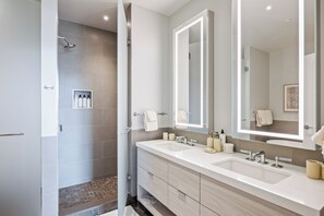 Un baño moderno con dos lavabos, un espejo grande y una zona de ducha.