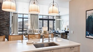 A modern kitchen with a large island, pendant lights, and a view of the mountains.