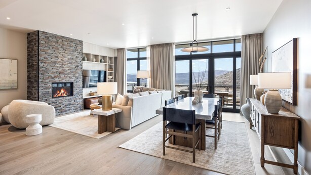 A modern living room with a fireplace, a dining area, and a sofa set.