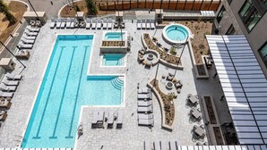 A rooftop swimming pool with multiple lanes, sun loungers, and a hot tub area.