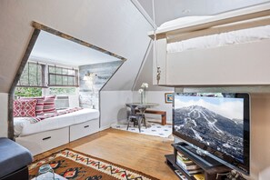 A cozy room with a white sofa, a TV, and a window overlooking greenery. - Best Views in Old Town overlook Main St & Ski Runs (Park City)