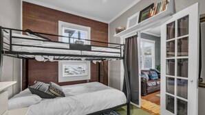 A bunk bed room with a desk, a bookshelf, and a view of the outside.