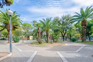 Une place publique dallée, agrémentée de palmiers et de lampadaires.
