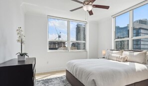 Enjoy a city view from the comfort of this stylish bedroom with a large bed and a ceiling fan.