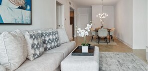 Relax in this serene living space with a light grey sofa, coffee table, and dining area.