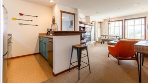 A kitchen with a central island, bar stools, and a dining area with a table and chairs. - Ski In/Out with Mountainside Views. Dog Friendly (Fernie)