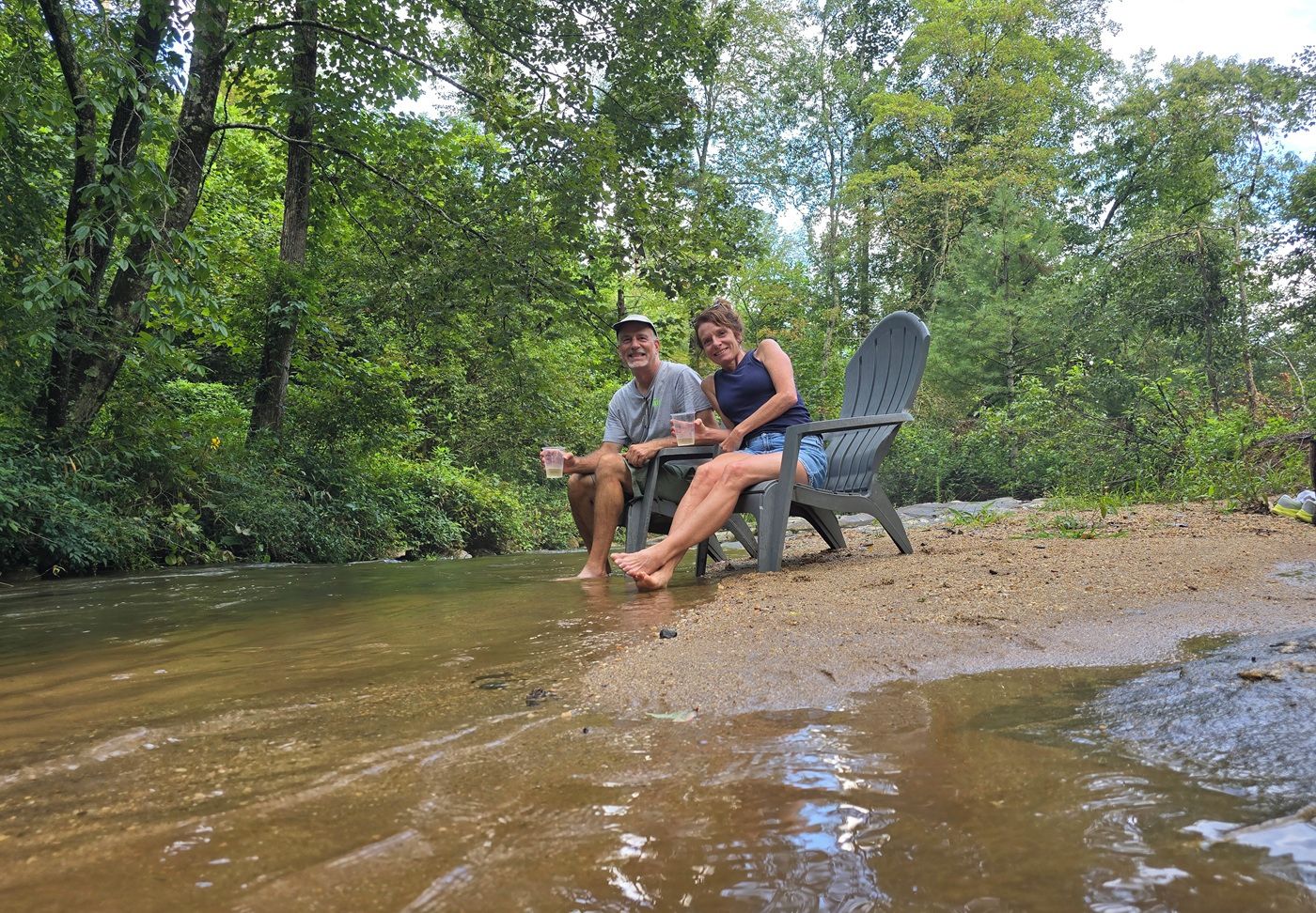 Two people relaxing by a creek in a natural setting.