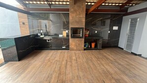 A spacious lobby with a wooden floor, a black marble reception desk, and a central pillar. - Complete House for Rest (Pedro Leopoldo)