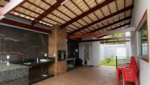 A spacious indoor area with a wooden floor, a black marble counter, and a red chair. - Complete House for Rest (Pedro Leopoldo)
