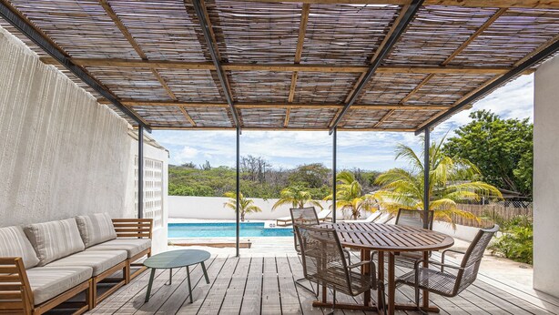 Eine überdachte Terrasse im Freien mit Pool, Holzmöbeln und Blick auf die umliegende Landschaft.