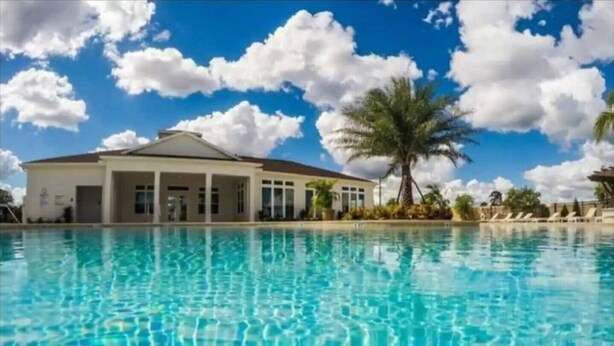 Una piscina cristalina con un edificio al fondo.