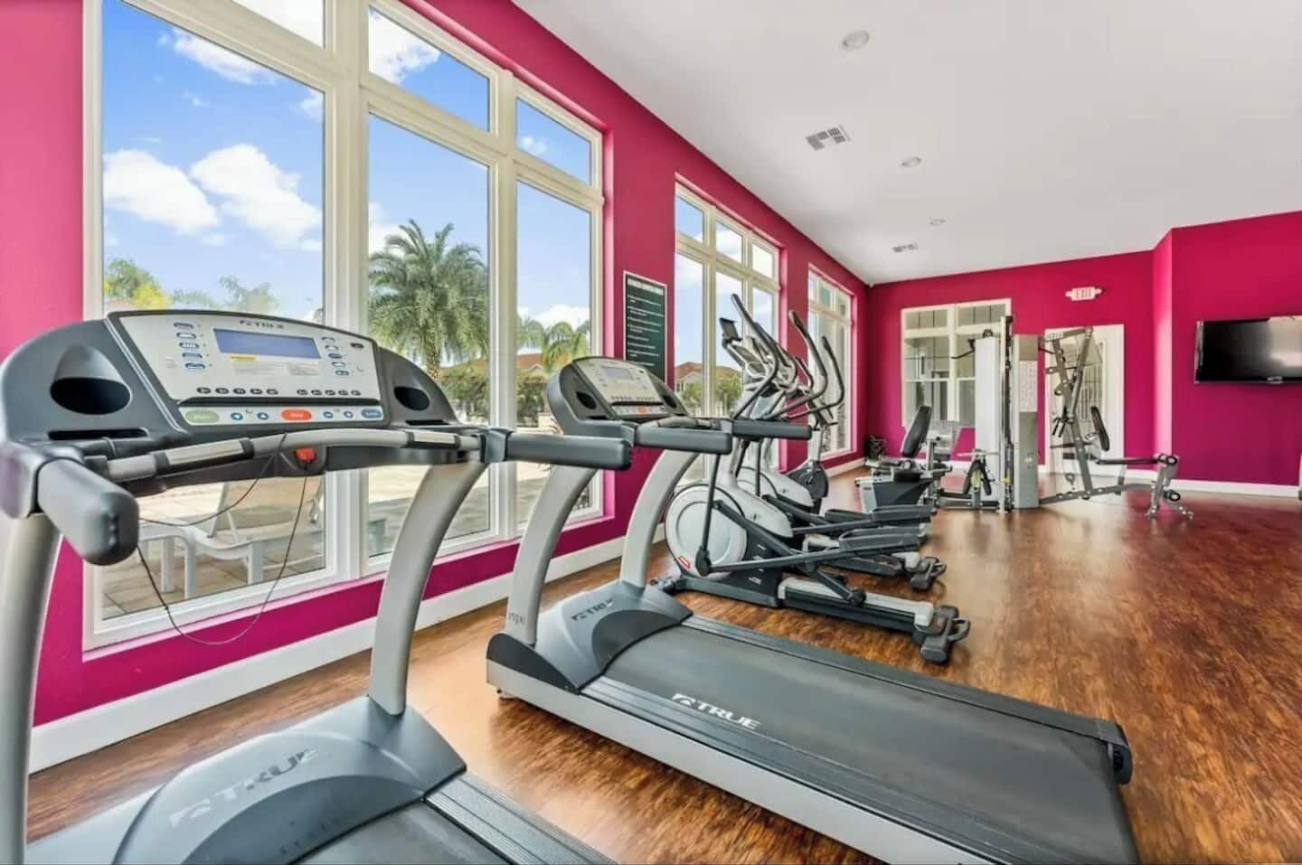 Ein Fitnessstudio mit Laufbändern, Ergometer und einem Fernsehbildschirm.