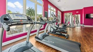 Un gimnasio con cintas de correr, bicicletas estáticas y una pantalla de televisión.