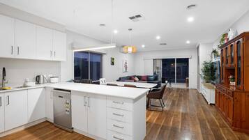 Enjoy casual dining in this stylish kitchen and dining area, featuring a central island, sleek cabinetry, and a comfortable sofa.