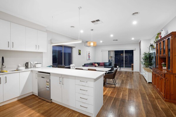 Enjoy casual dining in this stylish kitchen and dining area, featuring a central island, sleek cabinetry, and a comfortable sofa.