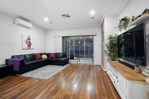 Relax in this stylish living room with a comfortable sofa, large TV, and sliding glass door leading to an outdoor area.
