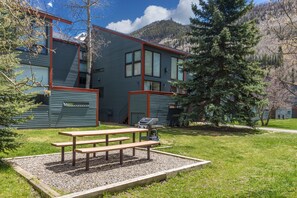 A building with a picnic table in front, surrounded by a grassy area and trees. - Experience luxury at Alpenglow at Telluride Lodge, a spacious 2 bed/2-bath condo (Telluride)